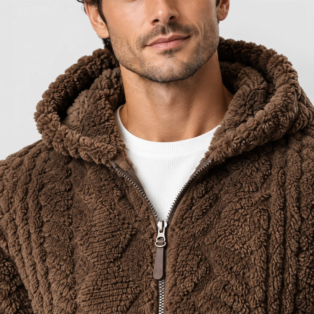 Close-up shot of the hood, zipper pull, and cable-knit texture on a dark brown men's fleece jacket worn over a white shirt.