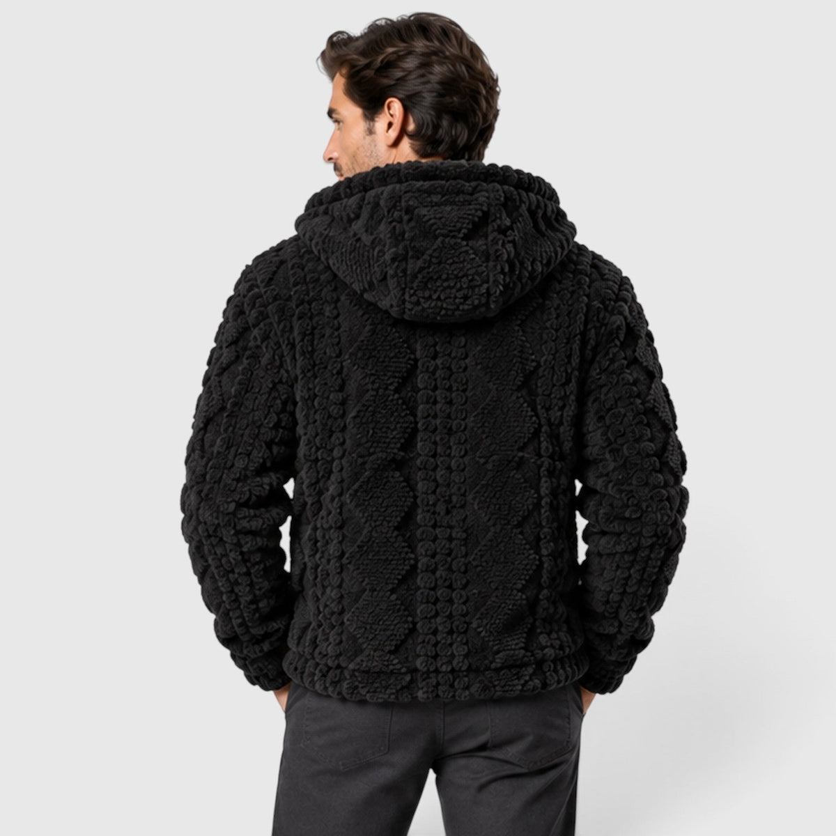 Back view of a man wearing a black hooded fleece jacket with embossed cable-knit details.