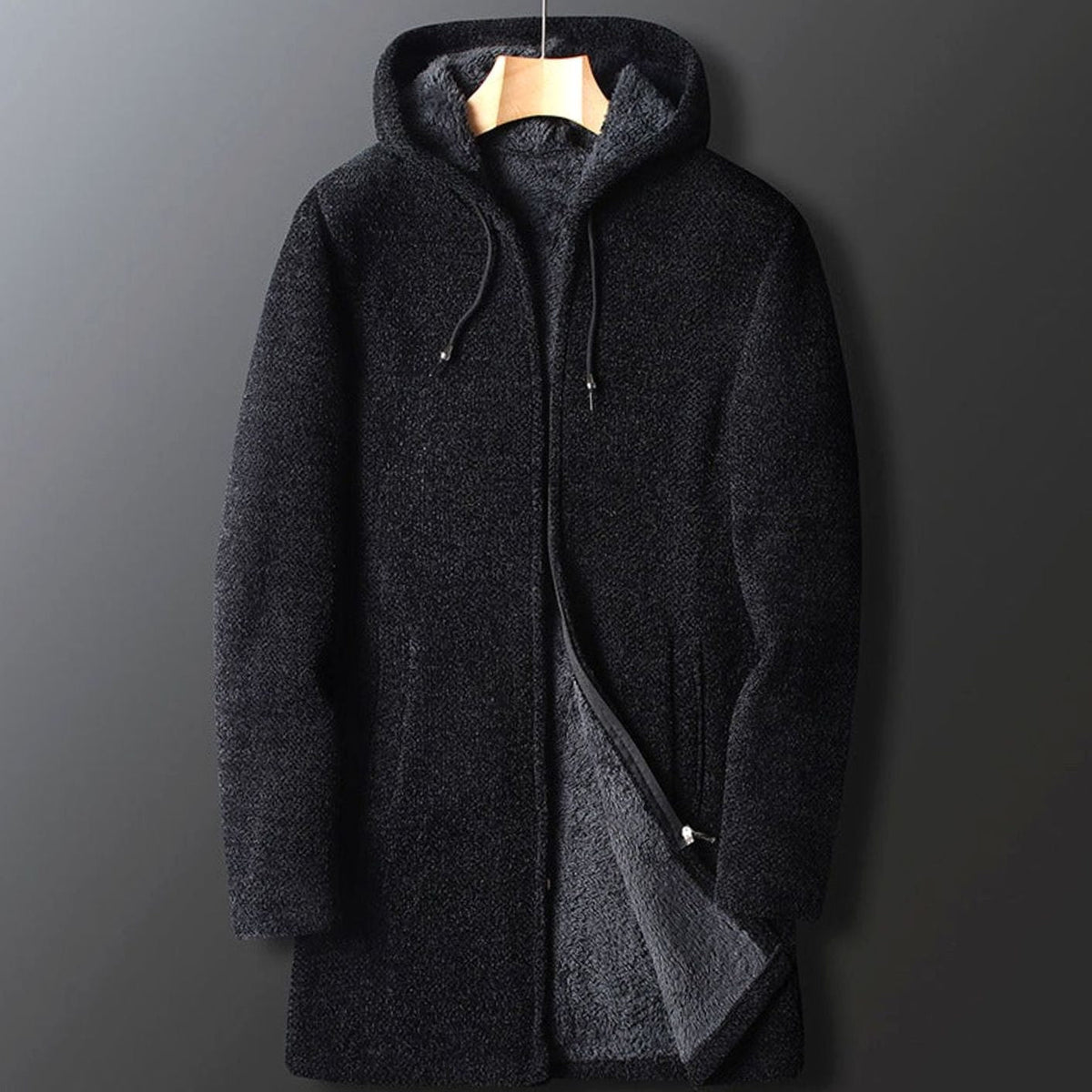 A men's longline black hooded coat with a textured knit outer shell and warm fleece interior lining, displayed on a hanger.