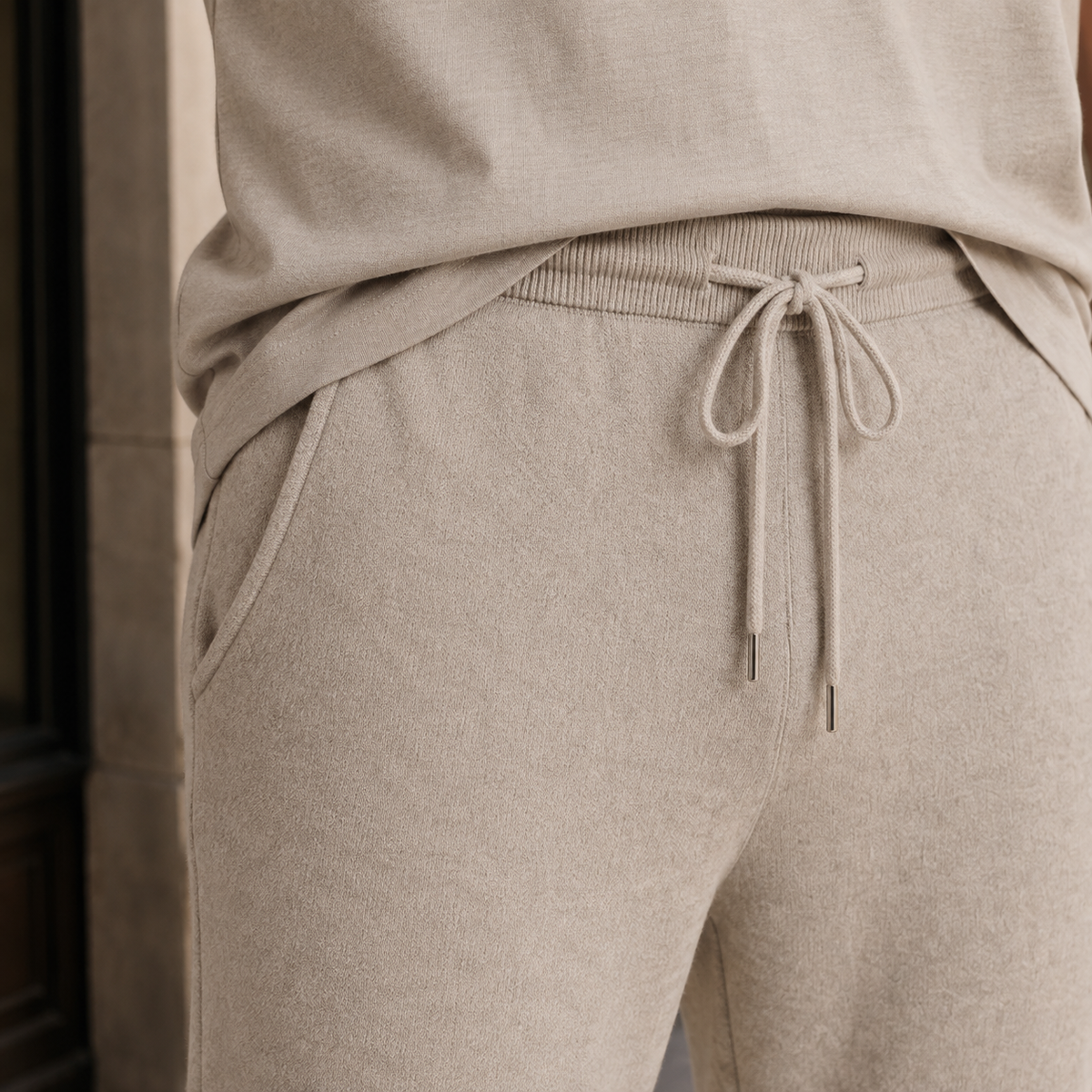Beige merino wool pants featuring a fine-knit texture, elastic drawstring waist, and a relaxed tapered fit.