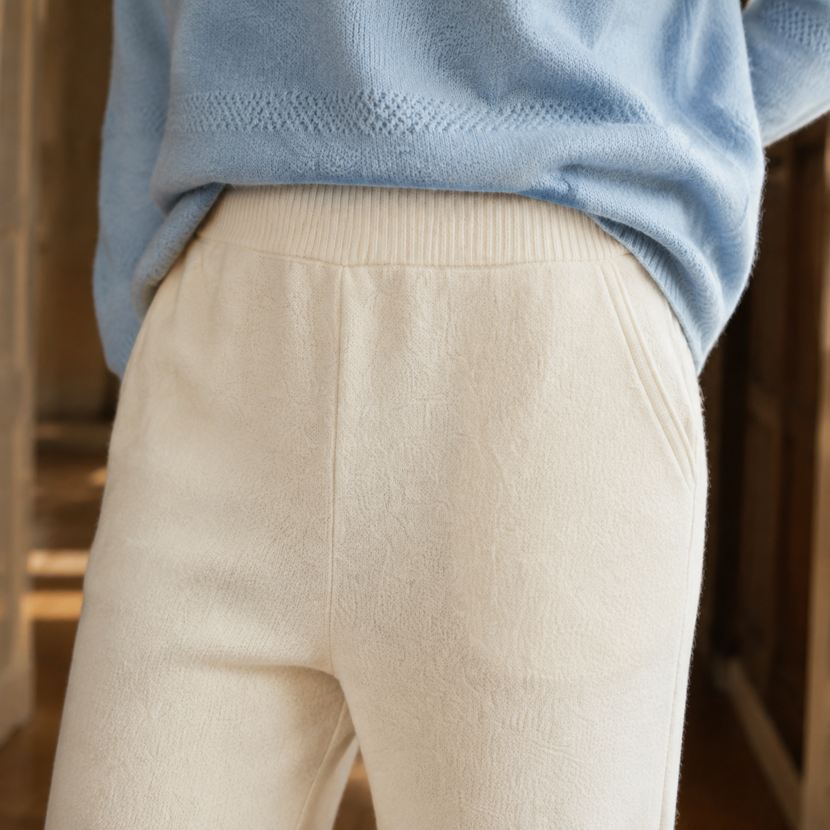 Ivory merino wool wide-leg pants featuring a high-rise elastic waistband and functional side pockets.