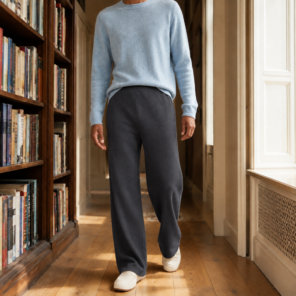 Dark gray merino wool pants featuring a relaxed wide-leg silhouette and elastic high-rise waist in a library setting.