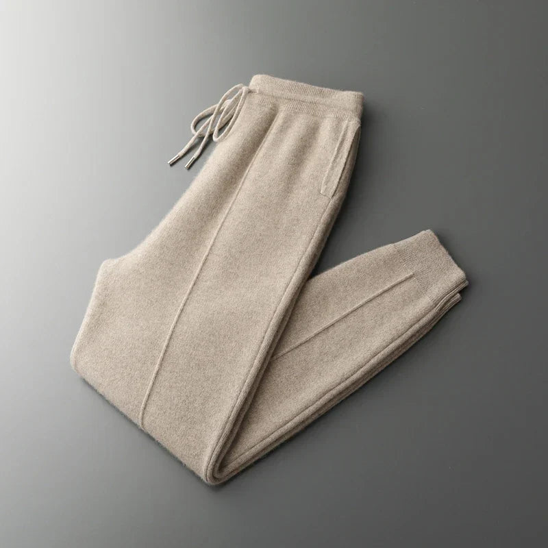 Beige merino wool trousers with a drawstring waist, straight-leg silhouette, and tapered ribbed ankles.