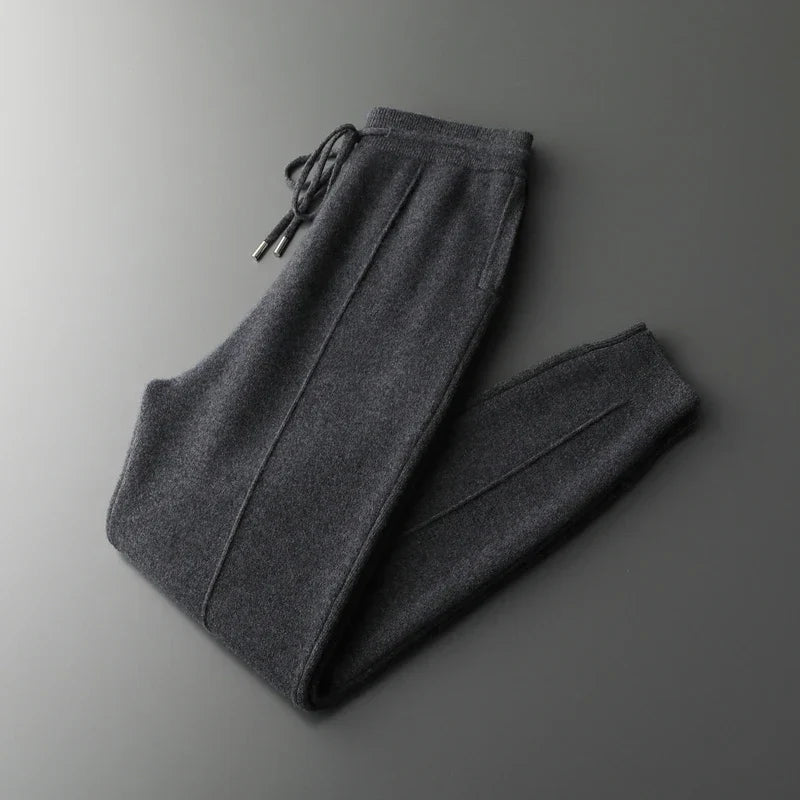 Dark gray merino wool trousers featuring a relaxed straight-leg fit, tapered ankles, and an adjustable drawstring waist.