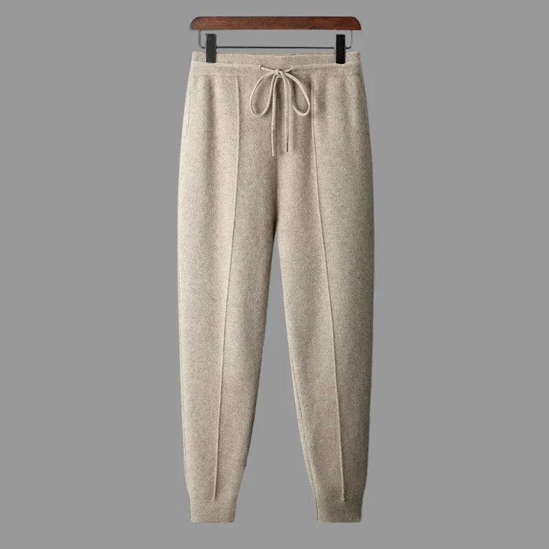 Beige merino wool trousers featuring a relaxed straight-leg fit, tapered ankles, and an adjustable drawstring waist.