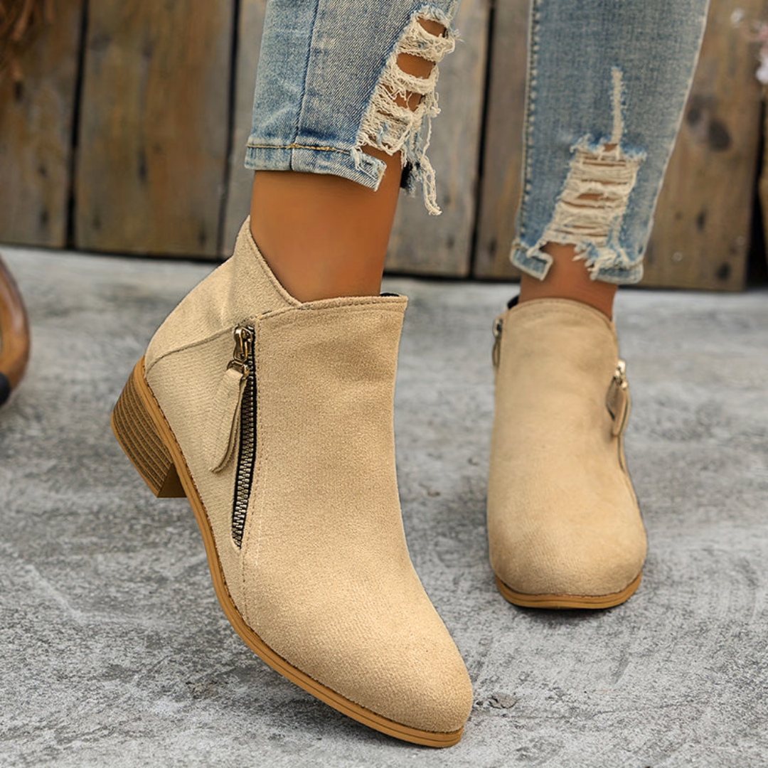 Beige brushed-finish almond toe booties with low block heels and an exposed diagonal side zipper.