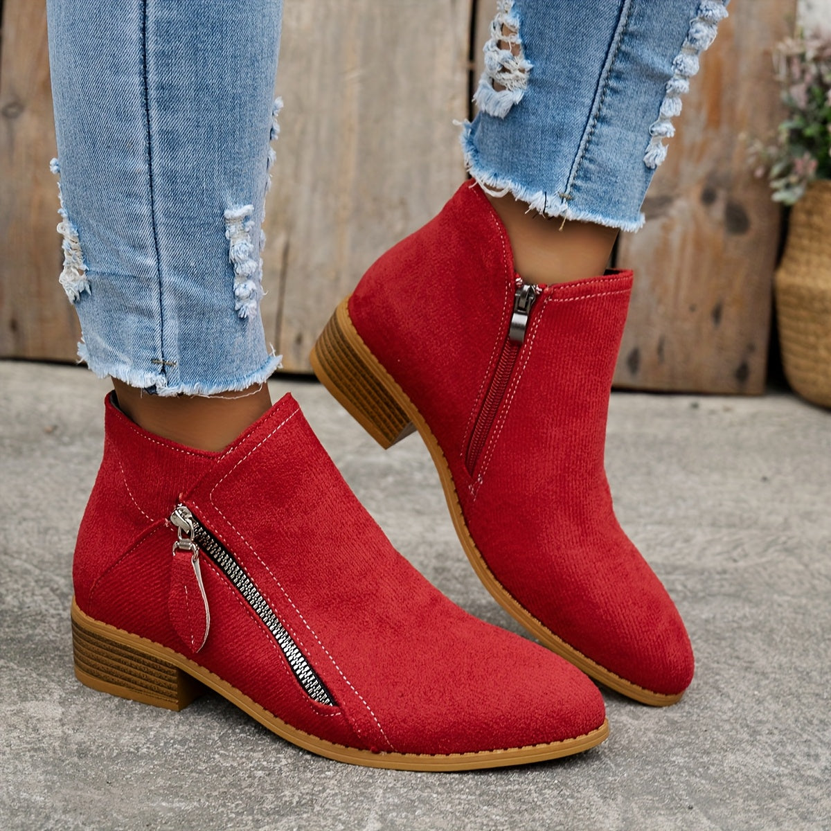 Red brushed-finish almond toe booties with low block heels and an exposed diagonal side zipper.