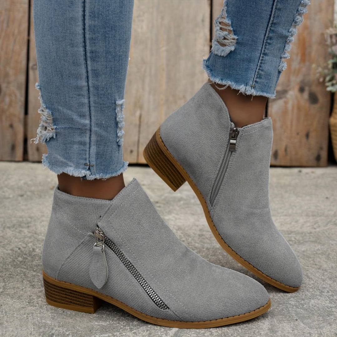 Grey brushed suede low-cut booties featuring an angled side zip, almond toe, and a stacked low block heel.