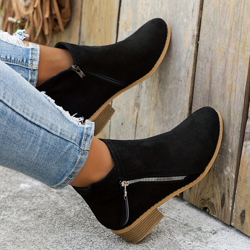 Black brushed-finish booties with an almond toe, low block heel, and diagonal silver side zip worn with distressed jeans.