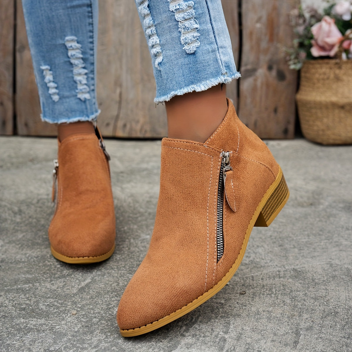 Tan brushed suede almond toe booties with an angled side zip and low block heel worn with distressed blue jeans.