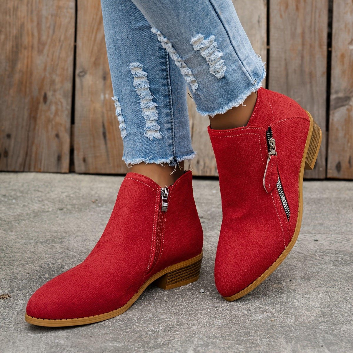 Red brushed-finish almond toe booties with low block heels and diagonal side zippers, styled with distressed blue jeans.
