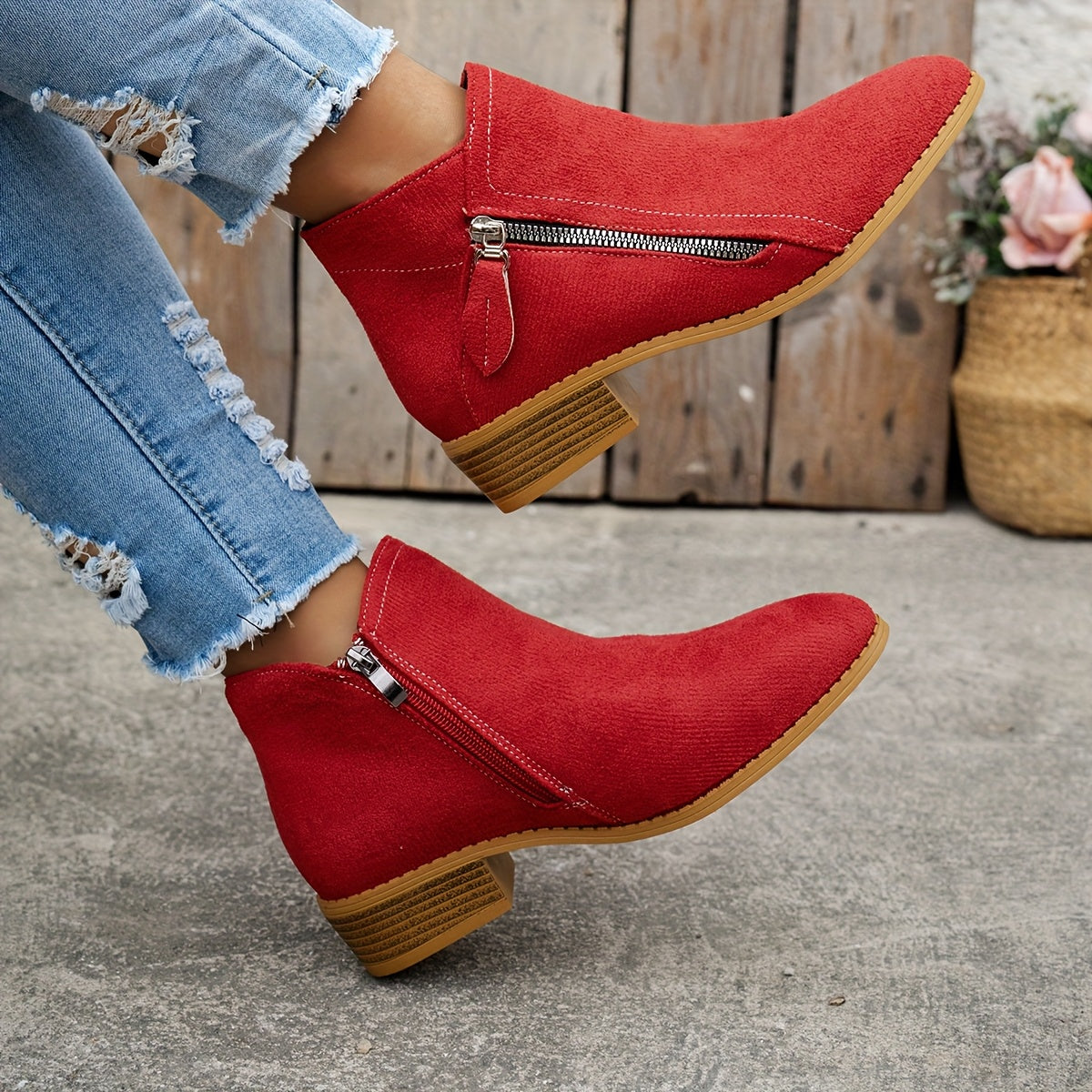 Red brushed-finish almond toe booties with low block heels and an exposed diagonal side zip, worn with distressed jeans.