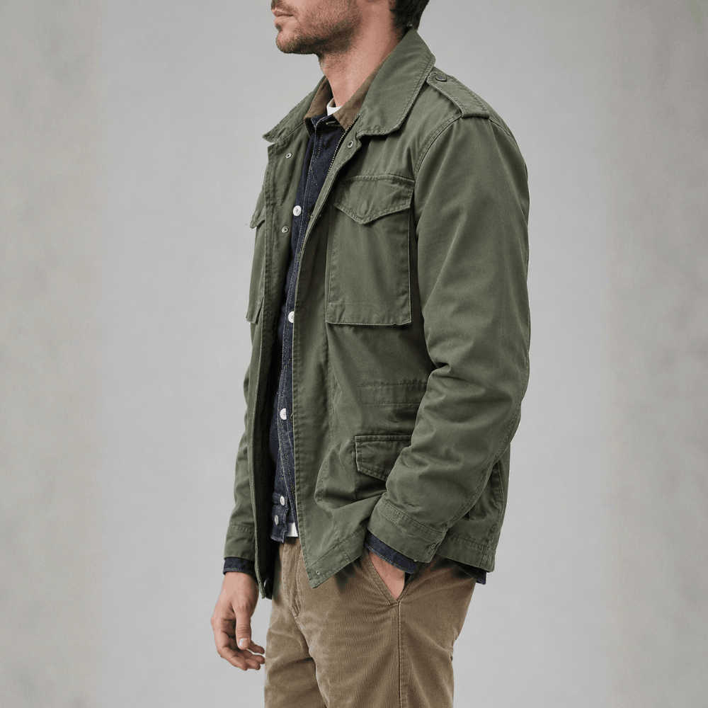 Side profile view of a model wearing the olive green military field jacket with shoulder epaulets and tan trousers.
