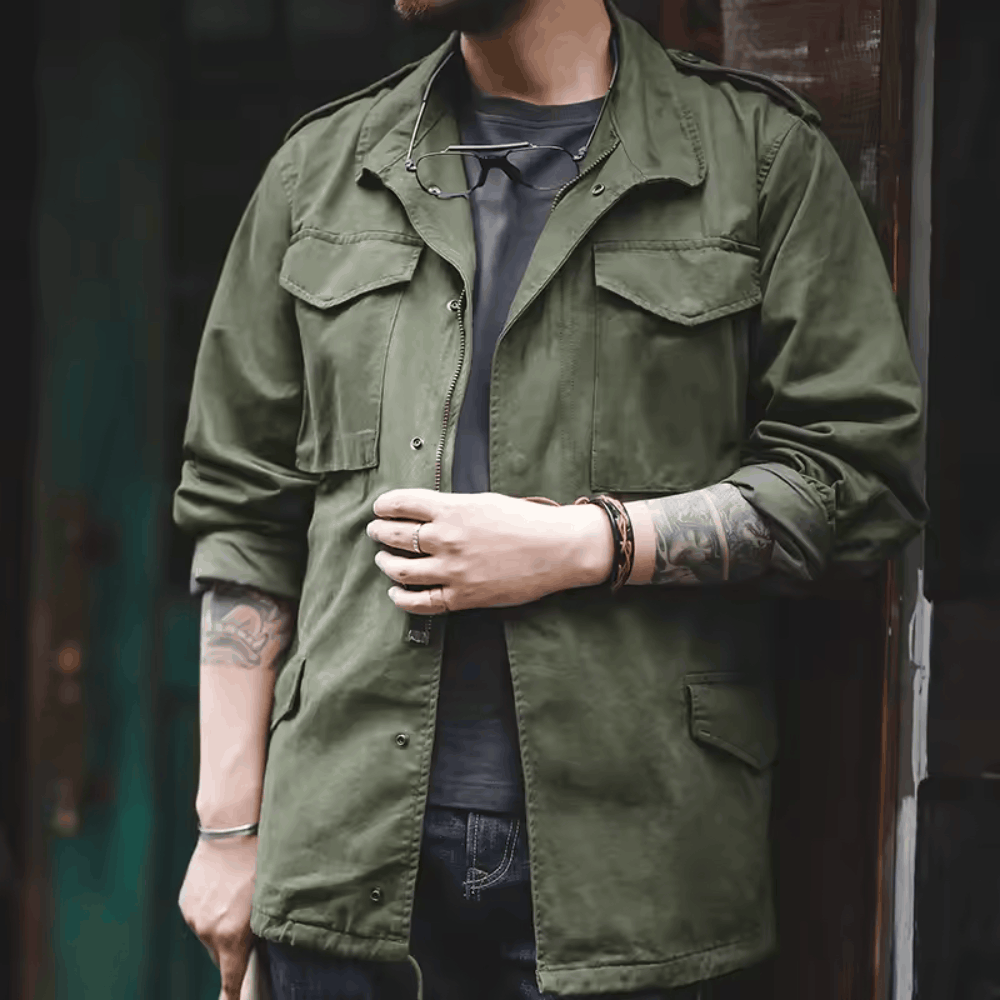 Close-up front view of a model wearing the olive green military field jacket with rolled sleeves, highlighting the chest flap pockets and epaulets.