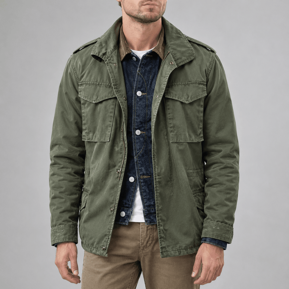 Front view of a model wearing an open olive green military field jacket featuring shoulder epaulets, four flap pockets, and a zip-and-snap front closure, layered over a denim jacket and white t-shirt.