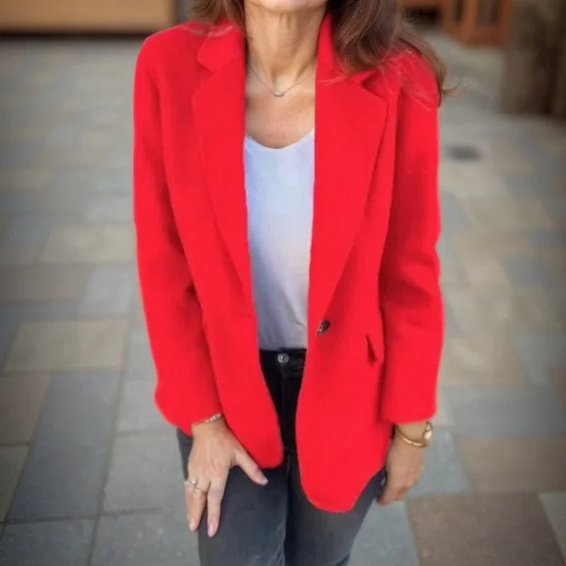 Red wool single-button blazer with a structured notched lapel, worn over a white top and dark denim jeans.
