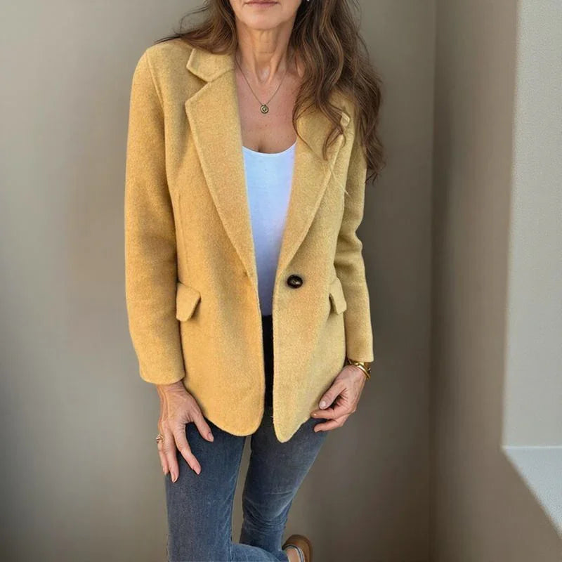 Mustard yellow wool single-button blazer with a structured notched lapel and welt pockets worn over a white top.
