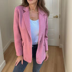 Structured pink wool blazer with a single-button closure, notched lapels, and welt pockets worn over dark denim.