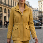Mustard yellow cotton blend utility jacket with a stand collar, zip-front closure, and adjustable drawstring waist.