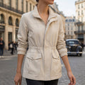Beige cotton blend utility jacket with a zip front, drawstring waist, flap pockets, and elasticized cuffs.