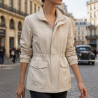 Beige cotton blend utility jacket with a zip front, drawstring waist, flap pockets, and elasticized cuffs.