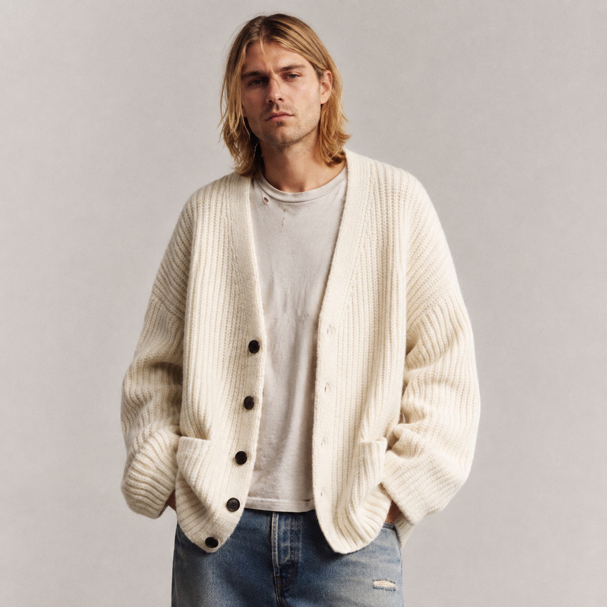Oversized cream chunky rib-knit cardigan with a V-neck, button front, and patch pockets worn over a white T-shirt.