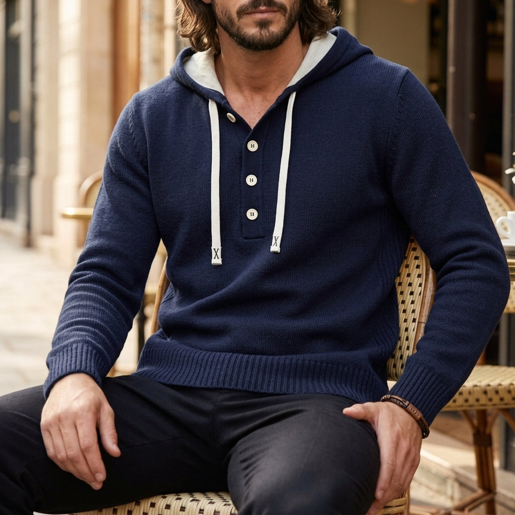 Navy blue oversized henley hoodie worn by a male model, shown seated with the button placket and kangaroo pocket visible.