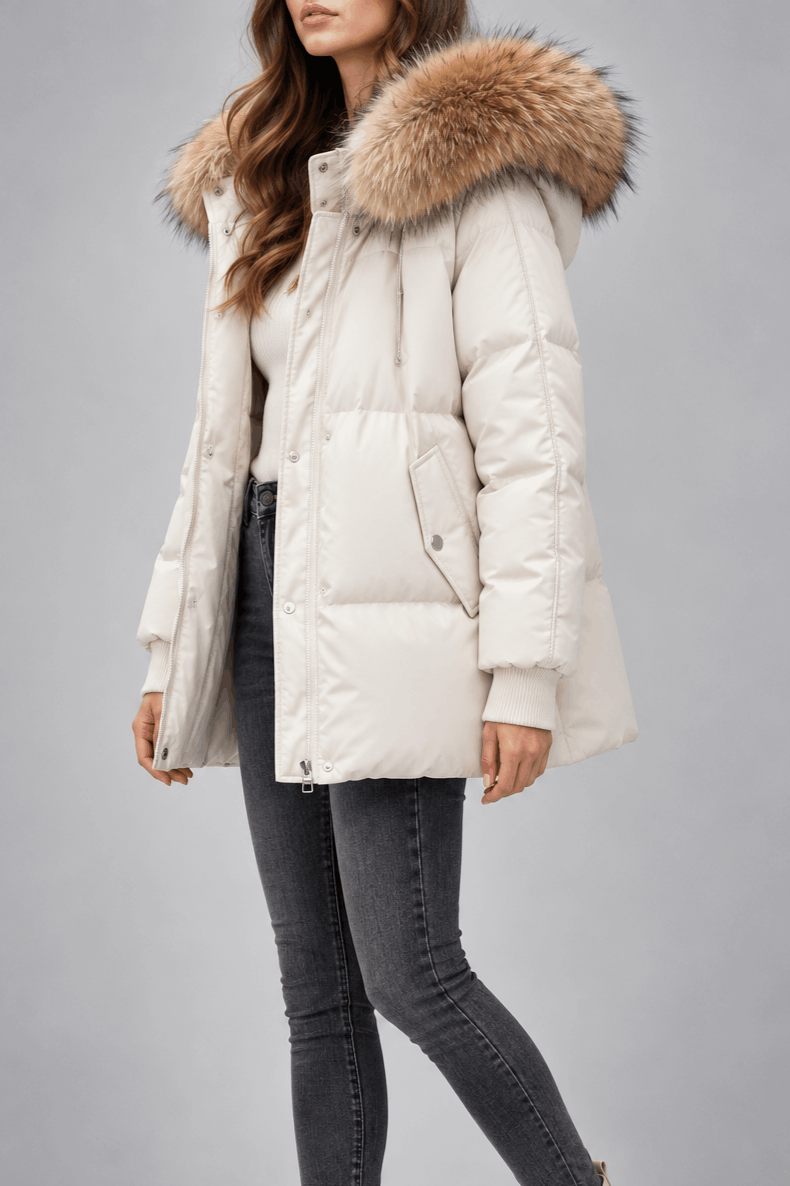 Oversized white puffer jacket with a plush-trim hood, quilted snap placket, and ribbed knit cuffs worn over dark jeans.