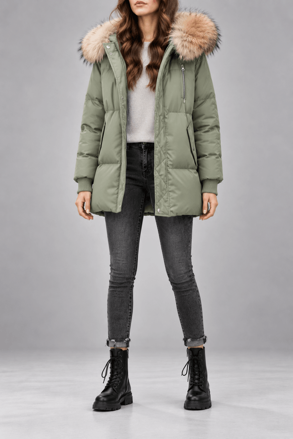 Sage green oversized puffer jacket with plush-trim hood, quilted snap placket, and ribbed knit cuffs worn over denim.