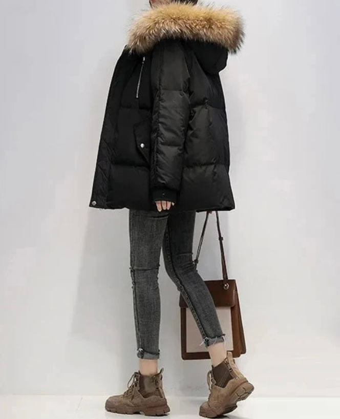 Oversized black puffer jacket with a plush-trim hood, quilted placket, and ribbed knit cuffs worn with dark skinny jeans.