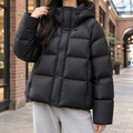 Black oversized puffer jacket with wide box quilting, padded hood, and snap-over zip front in a soft-sheen finish.