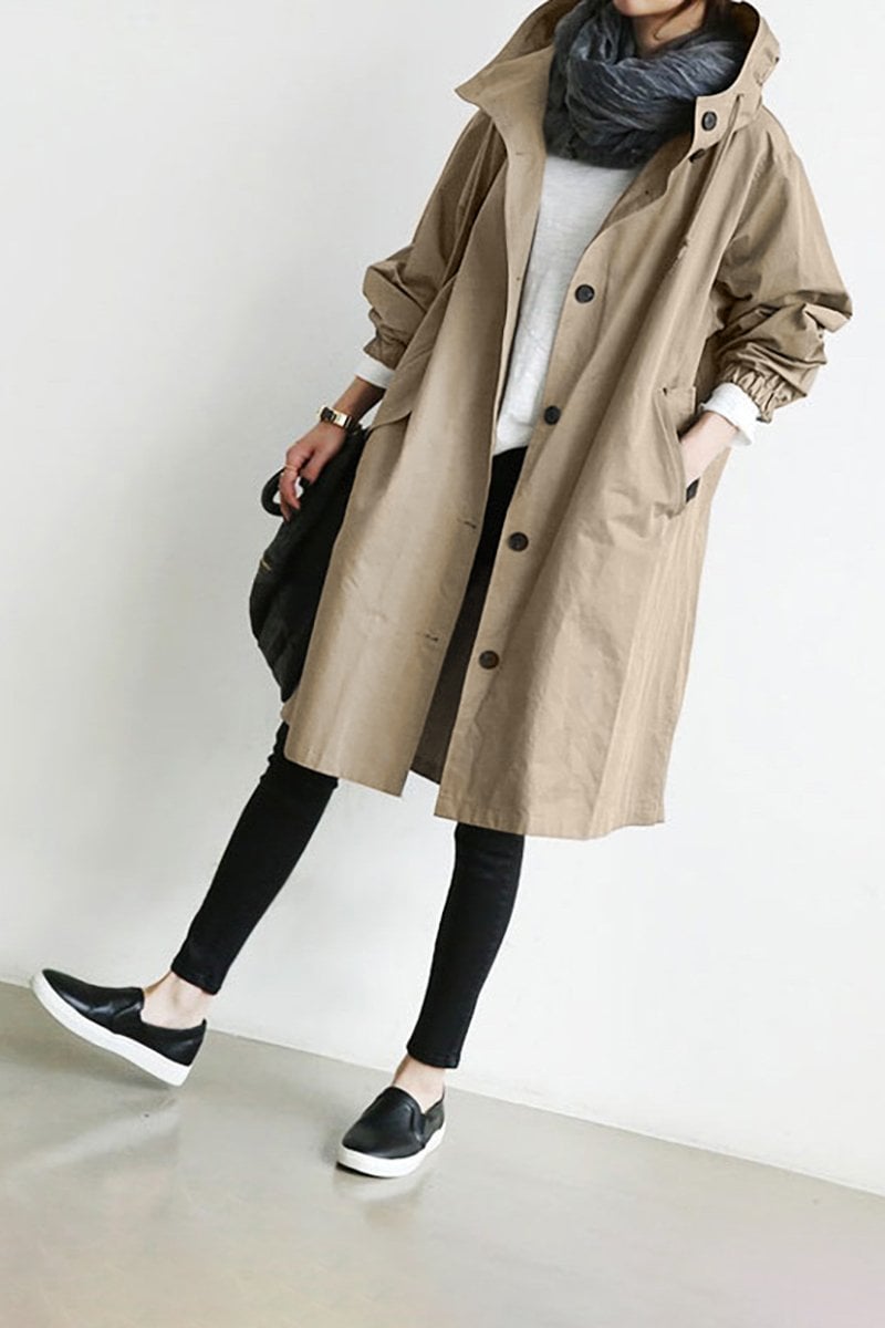 Oversized beige hooded trench coat in lightweight fabric with a button-front closure and deep slant hip pockets.