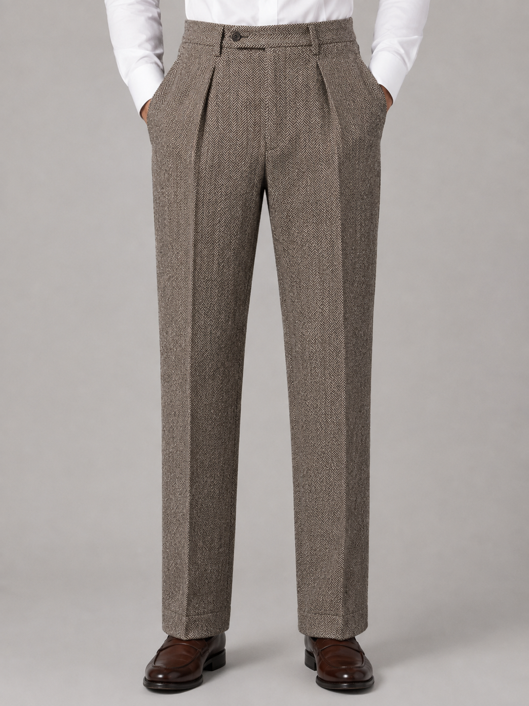 Brown herringbone trousers featuring a high-rise waist, front pleats, and a structured straight-leg silhouette.