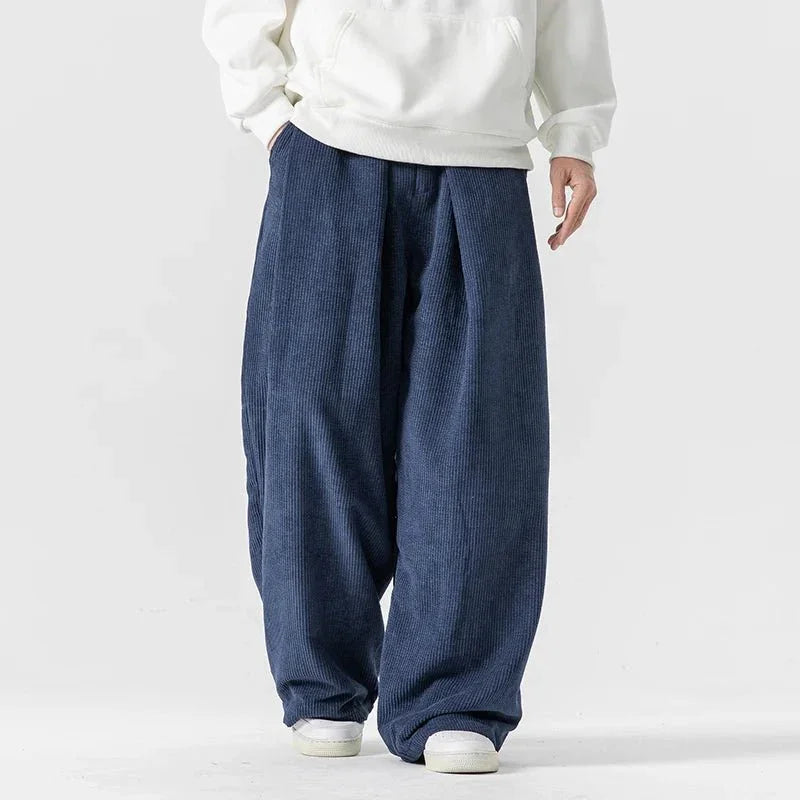 Navy blue wide-leg corduroy pants featuring deep front pleats, a relaxed fit, and a comfortable drawstring waist.