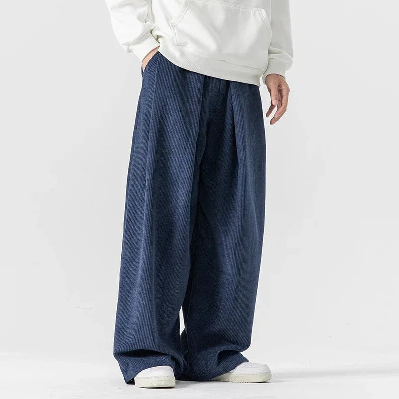 Navy blue wide-leg corduroy pants with deep front pleats, drawstring waist, and a relaxed, loose-fitting silhouette.