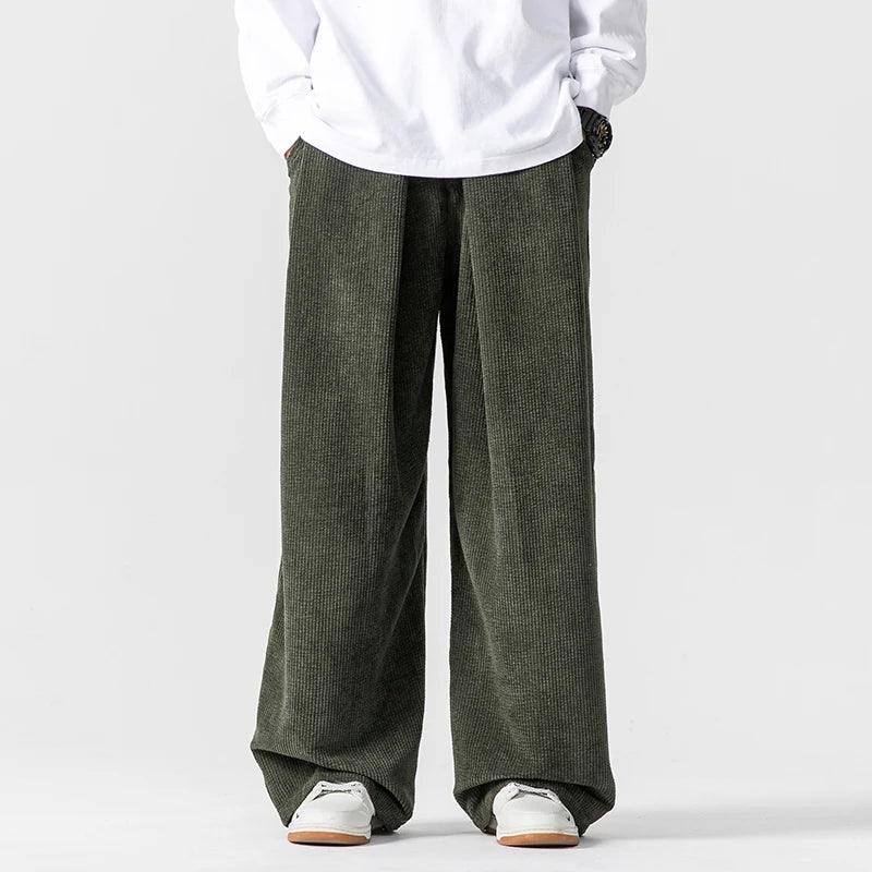 Olive green wide-leg corduroy pants featuring deep front pleats, a relaxed fit, and a comfortable drawstring waist.