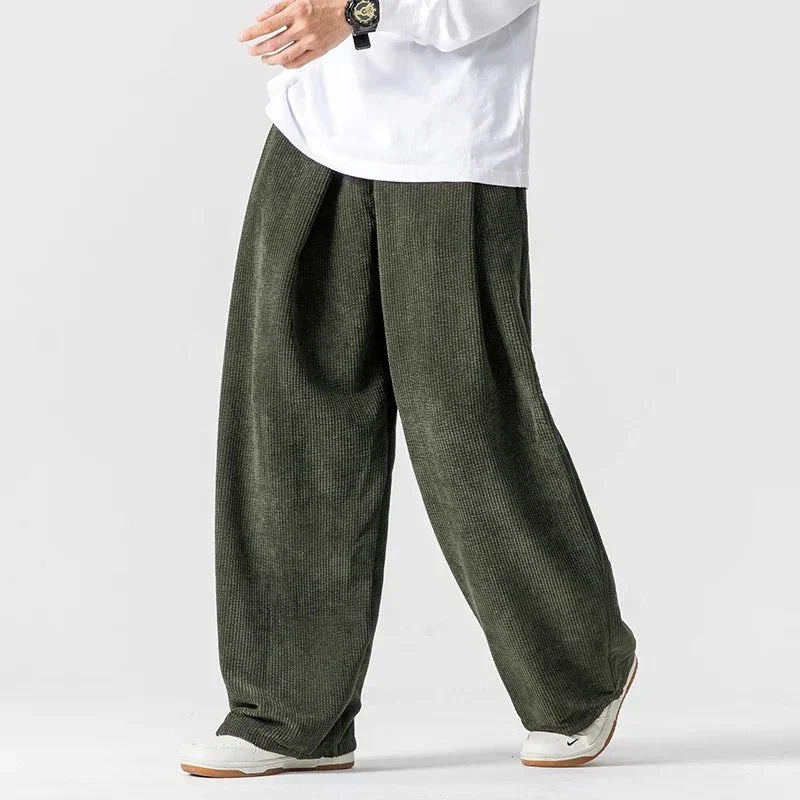 Olive green wide-leg corduroy pants featuring deep front pleats, a relaxed silhouette, and a comfortable drawstring waist.