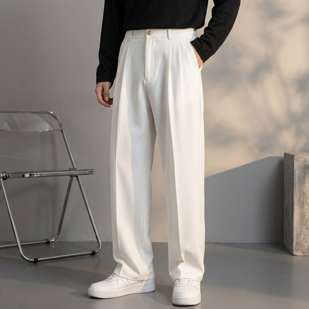 White pleated wool trousers with a relaxed, fluid drape and tailored front crease, worn with a black long-sleeve top.