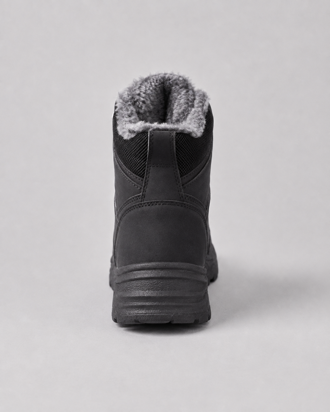 Black ankle boots featuring a plush-lined collar, matte finish, and a rugged, substantial lug sole from the rear view.