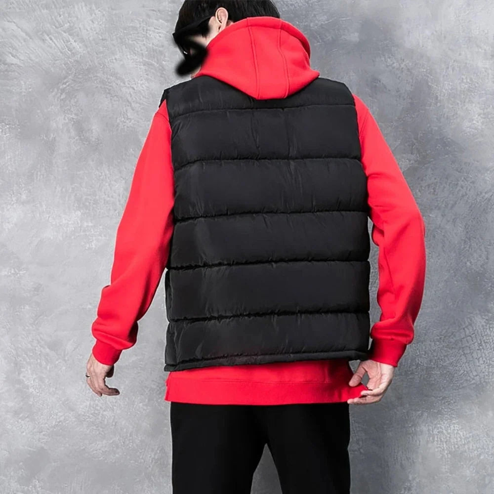 Back view of a male model wearing the black channel-quilted stand-collar puffer vest layered over a bright red hoodie.