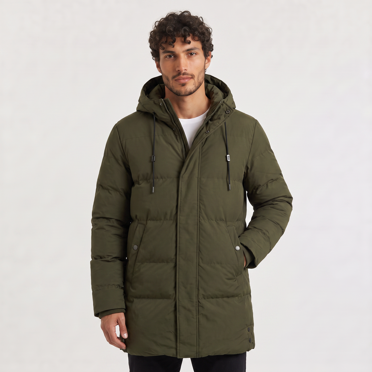 Olive green longline parka featuring horizontal quilted padding, a drawstring hood, and a concealed zip placket.