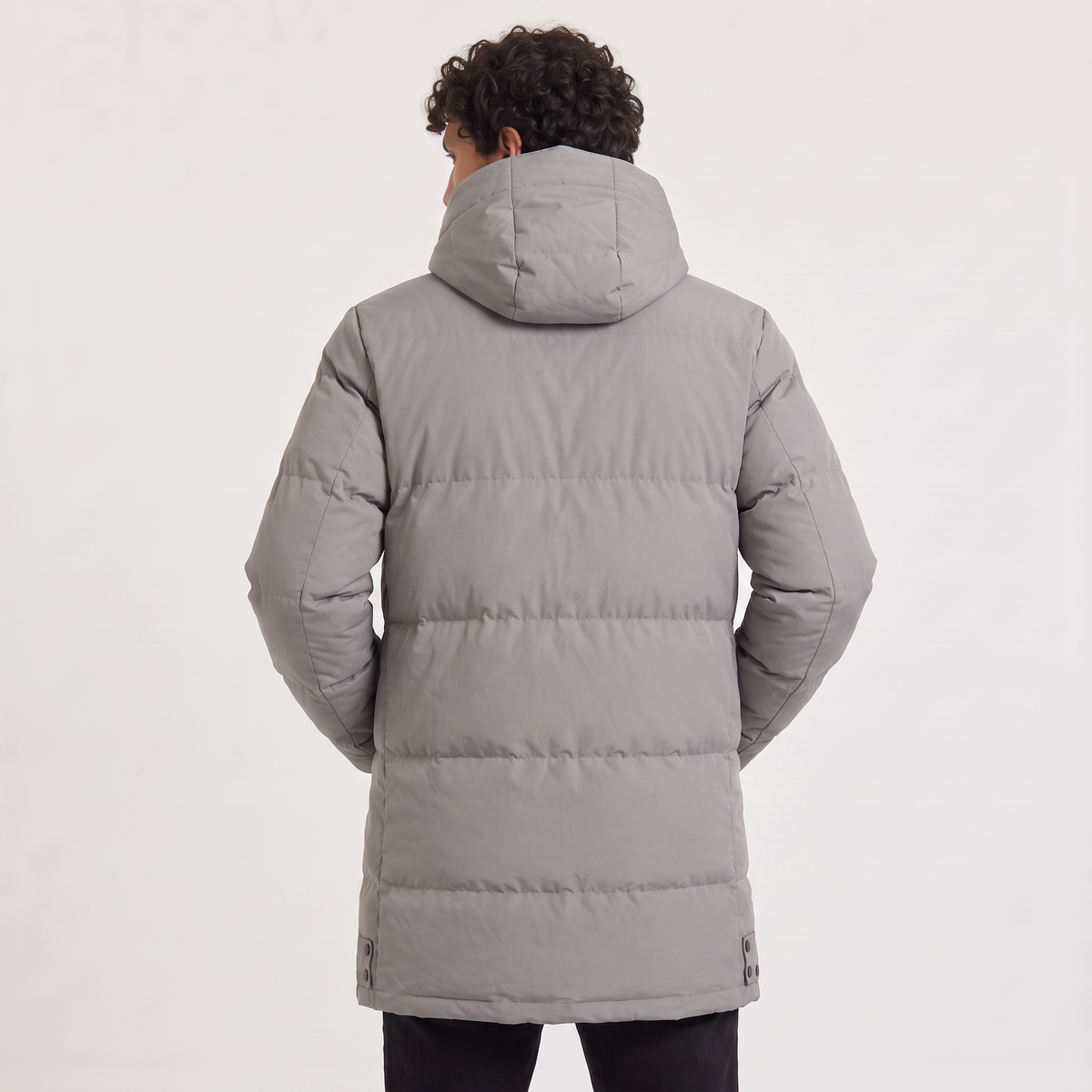 Gray quilted longline parka with horizontal padding, an attached drawstring hood, and a clean, minimalist back silhouette.