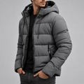 Charcoal gray quilted puffer jacket with an adjustable drawcord hood, vertical zip pockets, and a tailored hip-length fit.
