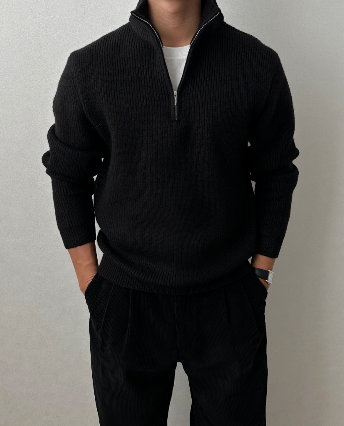 Black quarter-zip knit sweater featuring a stand collar and textured knit, styled with black trousers.
