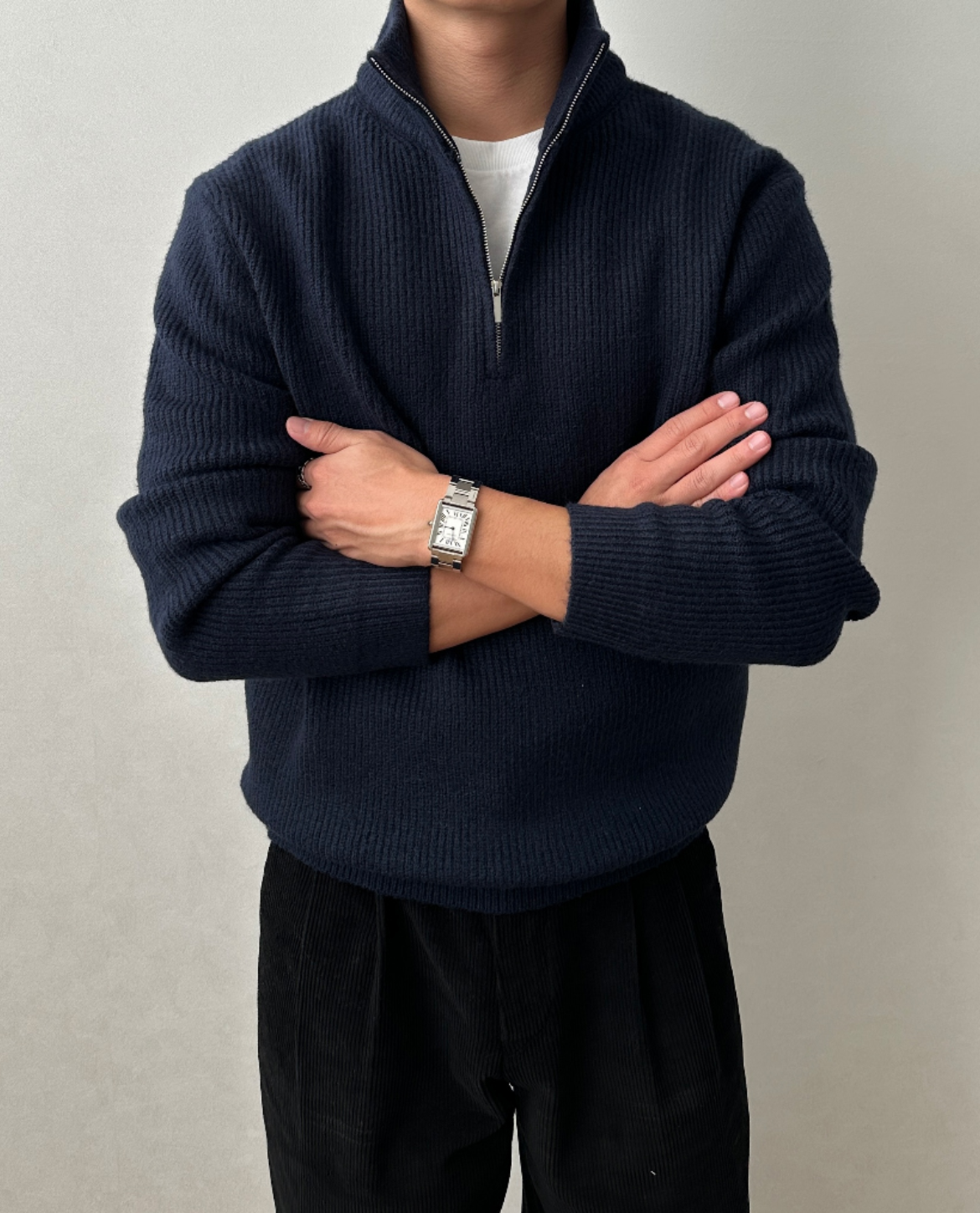 Navy quarter-zip knit sweater featuring a stand collar and textured knit, shown with arms crossed.