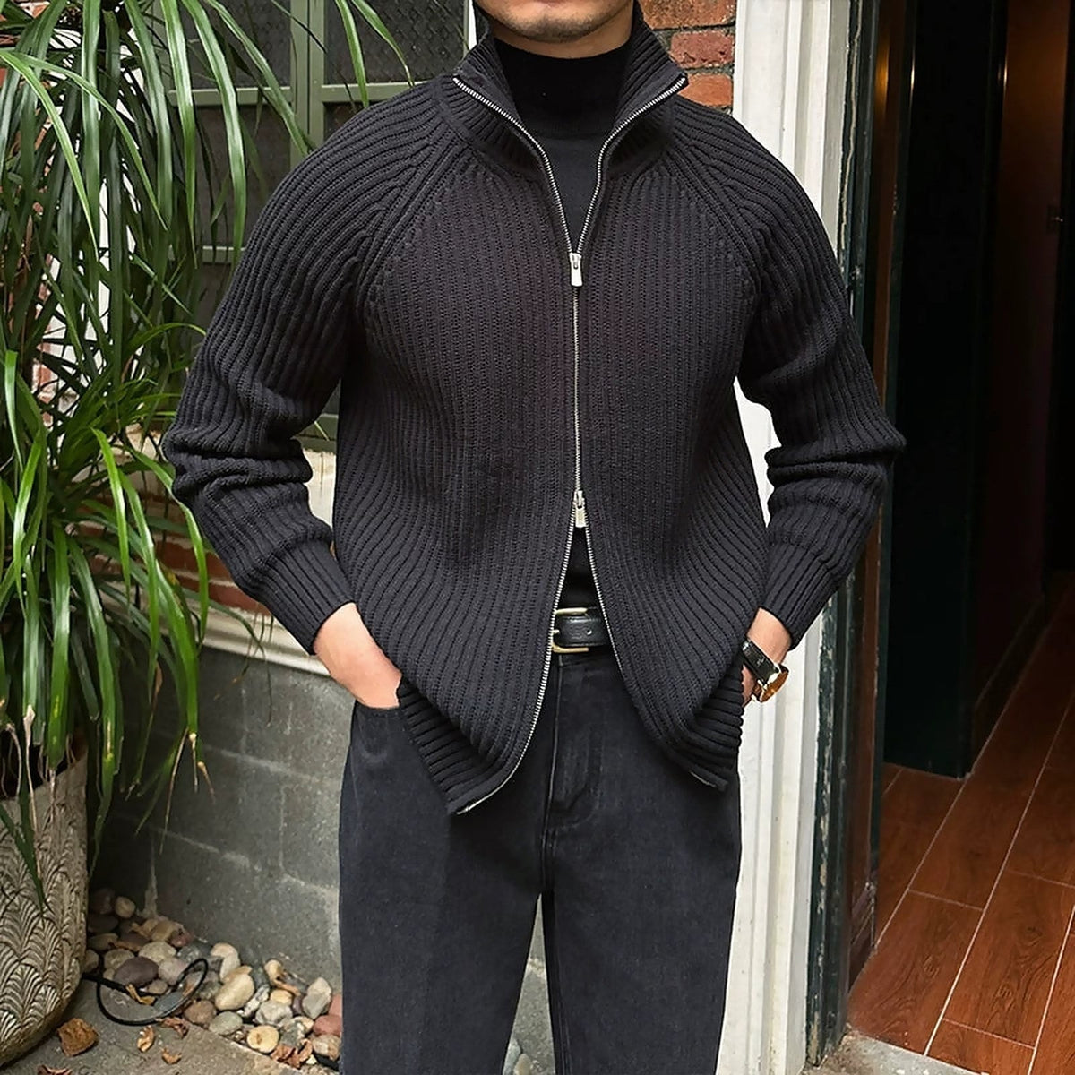 Black ribbed linen-blend knit cardigan with a zip-up front, relaxed fit, and structured collar worn over a black turtleneck.