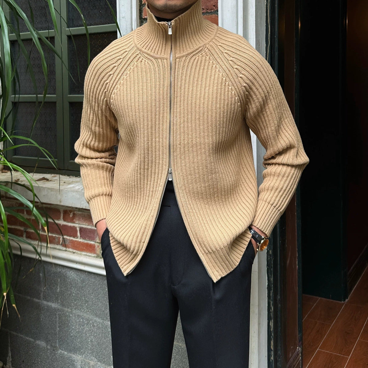 Beige linen-blend knit cardigan with a full-zip front, ribbed mock neck, and relaxed fit worn over black trousers.