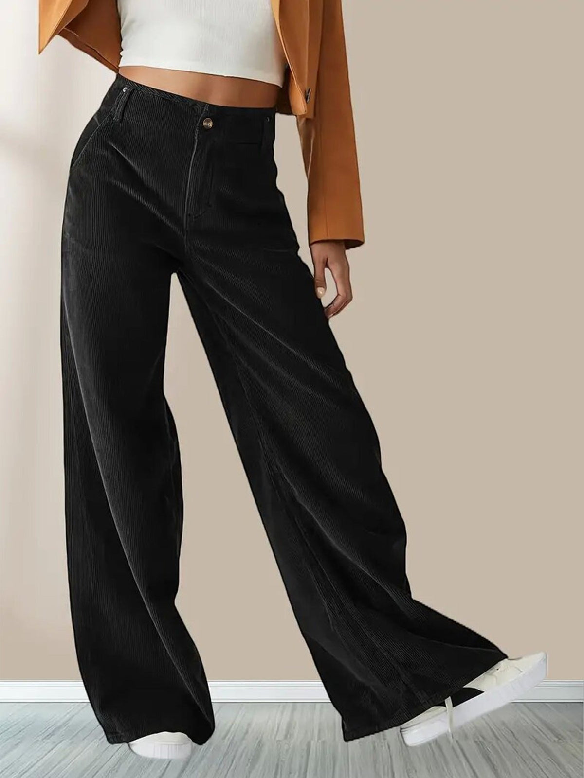 Black wide-leg corduroy pants featuring a button-zip fly, slant pockets, and a relaxed, fluid fit worn with sneakers.