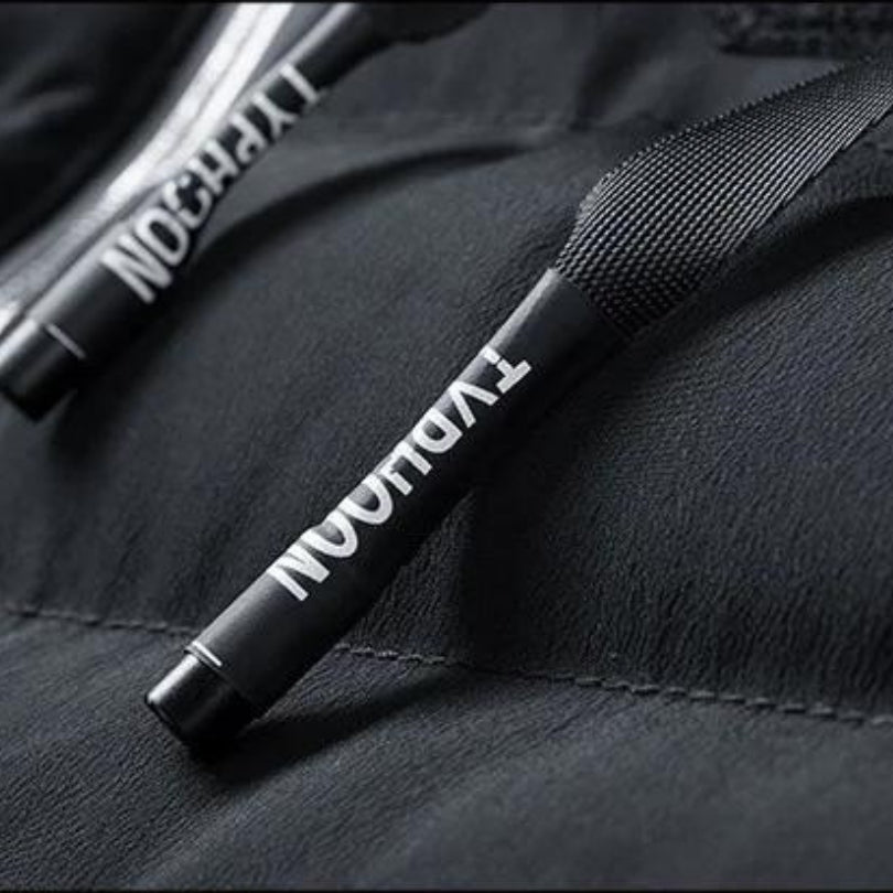 Close-up detail shot highlighting the rubber-tipped drawstring toggles with typography detailing on the hooded puffer vest.