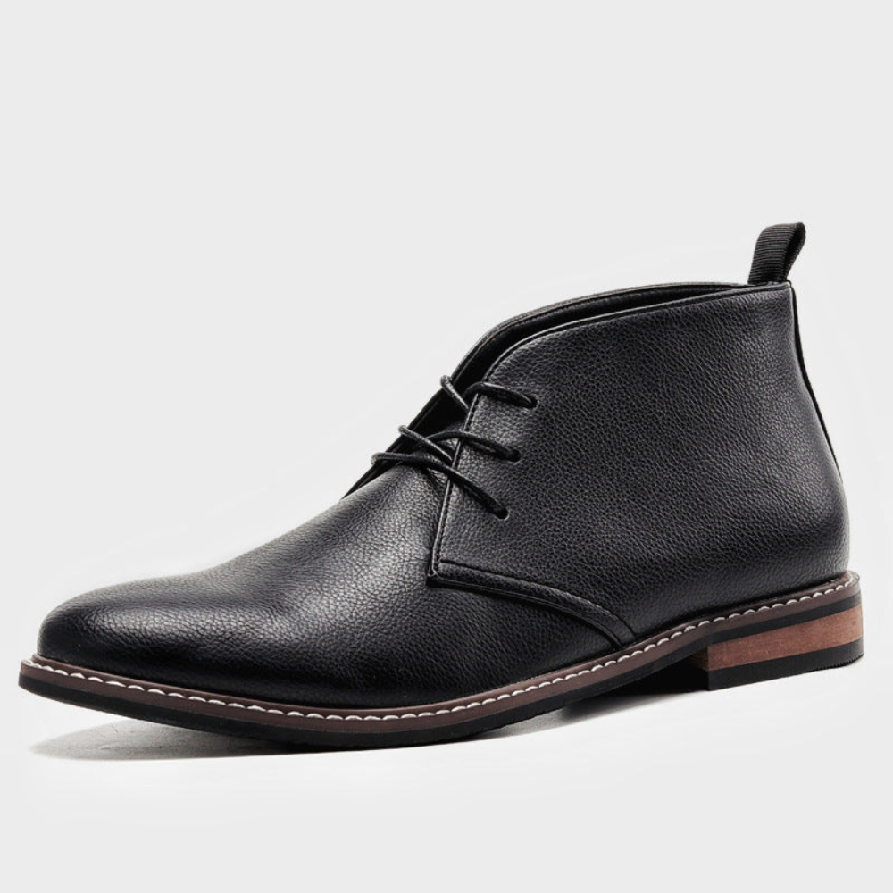 Black leather chukka boots with a rounded toe, short lace run, visible panel stitching, and a low stacked wooden heel.
